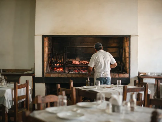 La parrilla a la vista al fondo del salón, con el parrillero de espaldas