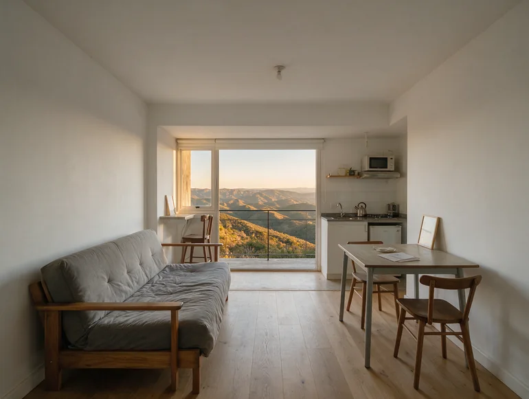 Ambiente con sofá cama y el ventanal abierto a la vista de las sierras